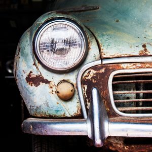 Detail of the front headlight of an old car in garage