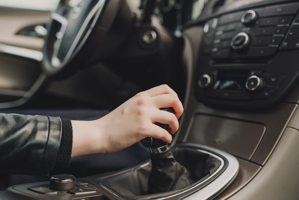 Close up of hand of female driver shifting gear stick before driving car