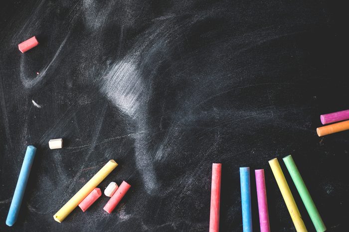 Black old empty chalkboard for copy space with colorful pieces of chalk.