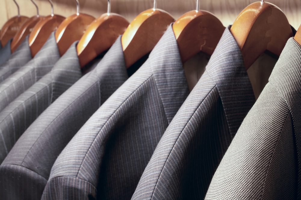 Row of men's suit jackets hanging in closet