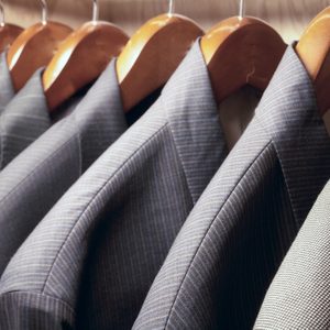 Row of men's suit jackets hanging in closet