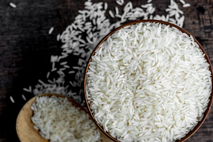 Jasmine rice in wooden bowl with wood ladle on old wood background, Dark tone, Copy space