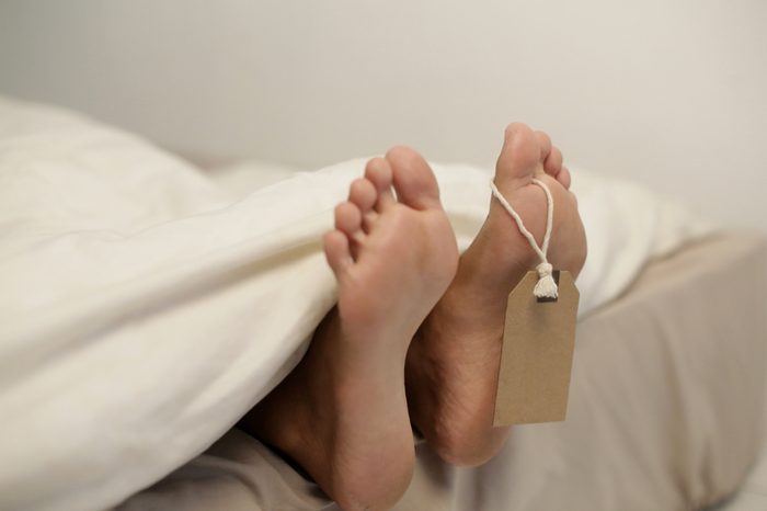 Dead person body lying in the morgue. Grungy photo of feet with toe tag on a morgue table.