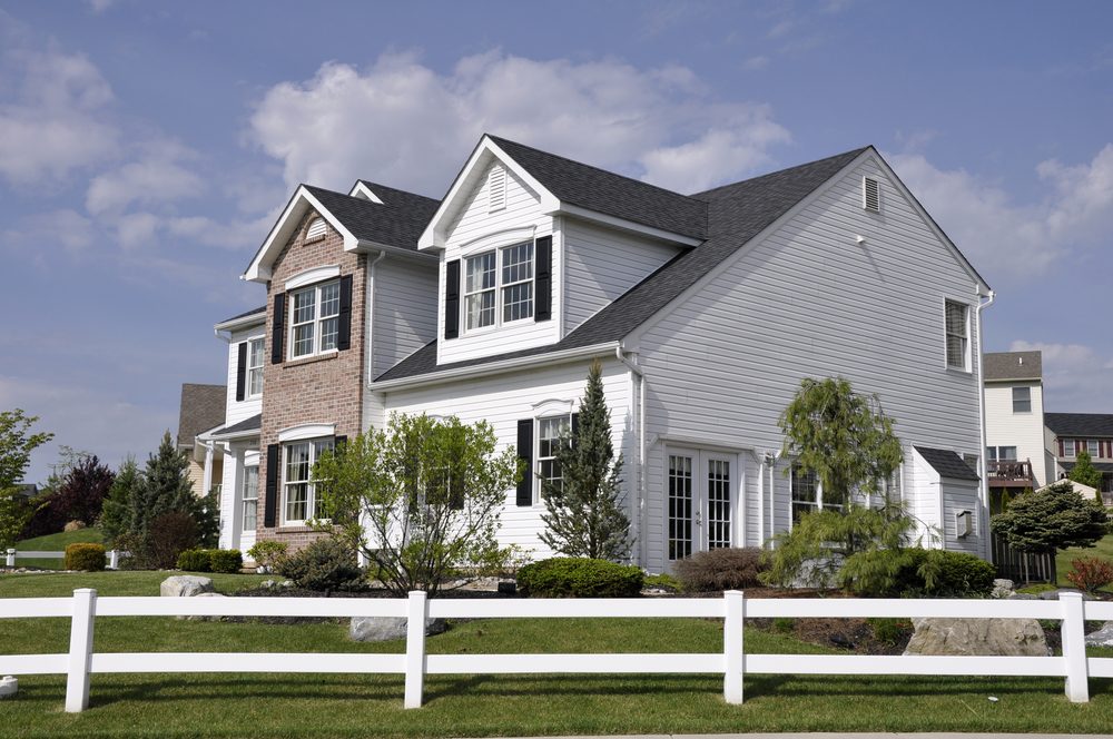 Two story modern home with a white wooden fence around the yard