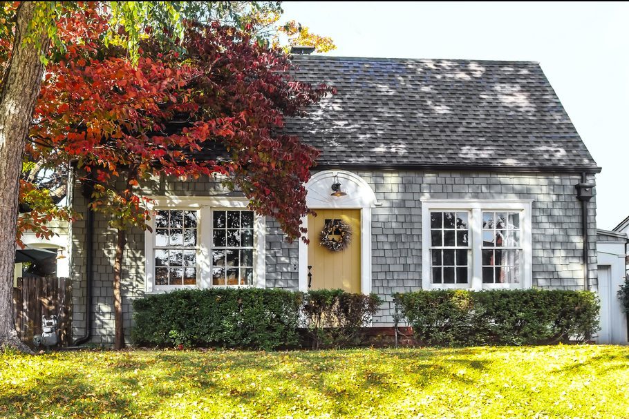 Beautiful grey wood shingle cottage with autumn trees and wreath on door