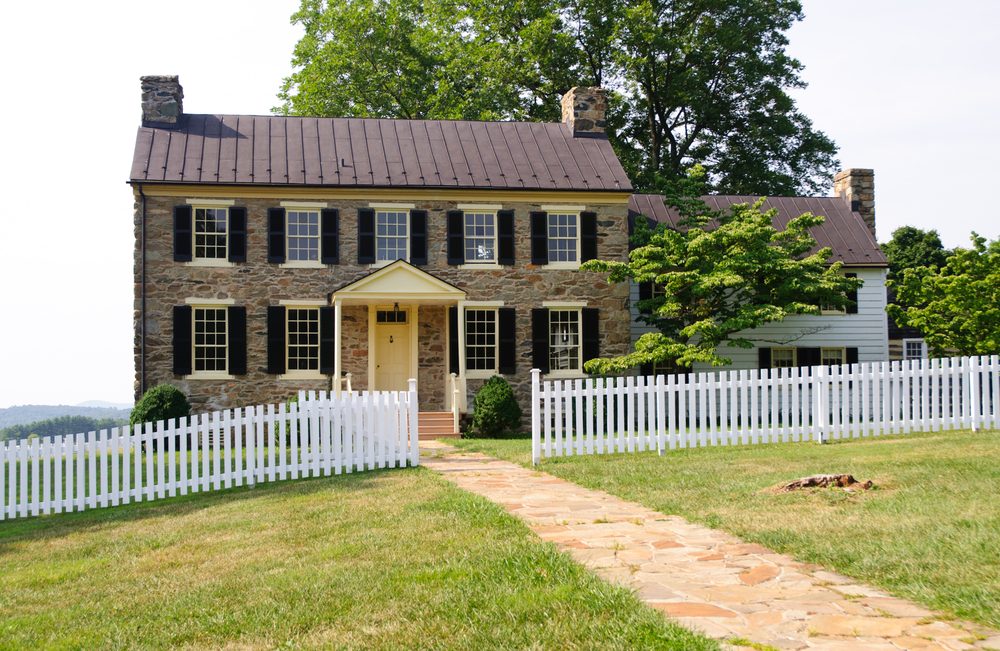 historic house and white pickett fence on a hill