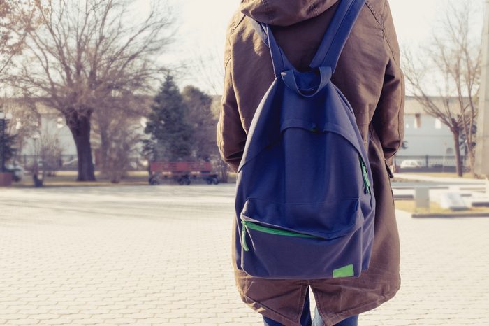 Rear view of hipster girl carring backpack on her back, copyspace.