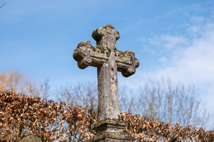 Old weathered stone cross crucifix on cemetary in Girsterklaus, Luxxembourg.