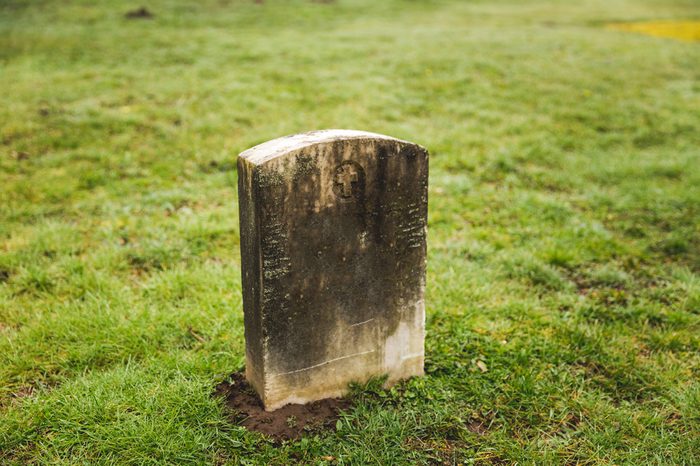 Grave yard tomb stone in misty, green cemetery.