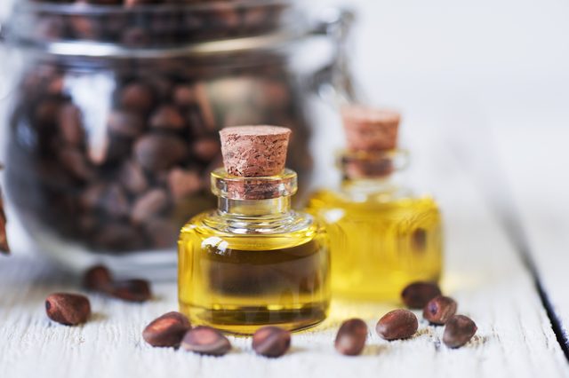 The cedar oil in a glass bottle on a white wooden background. Source of essential fatty acids for healthy nutrition