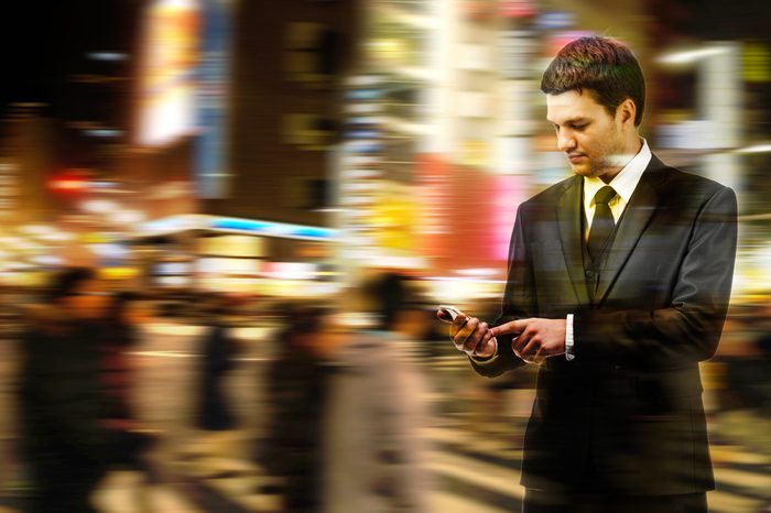 Double exposure of businessman uses the smart phone on the city street, and motion blur background