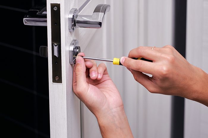 handyman repair the door lock in the room, Man fixing lock with screwdriver, Close-up of repairing door, professional locksmith installing or repairing a new deadbolt lock on a house