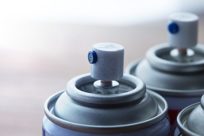 Aerosol spray cans nozzle close up. Several spray cans with light in background. Shallow depth of field.