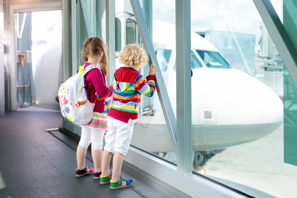 Kids at airport. Children look at airplane. Traveling and flying with child. Family at departure gate. Vacation and travel with young kid. Boy and girl before flight in terminal. Kids fly a plane