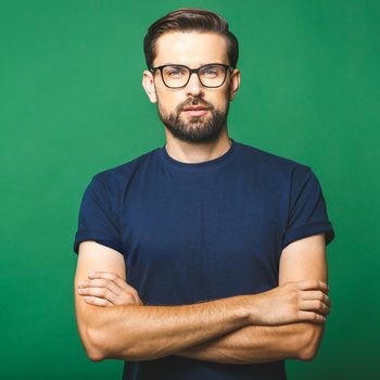 A portrait of young handsome man in casual isolated on green background with glasses.