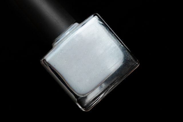 a bottle of grey nail Polish on black background