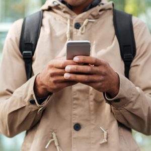 Person in a beige raincoat using their cellphone