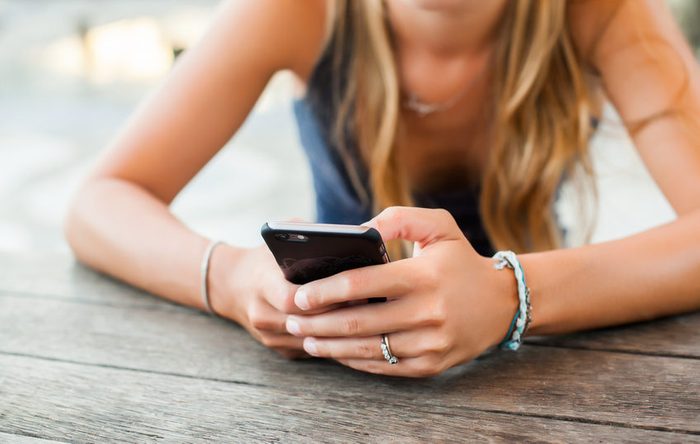 pretty girl in a cafe works on the phone, keep your smartphone in your hands, writes a letter, social networking, messaging, office work,vacation,posting photos to instagram, outdoor portrait,close up