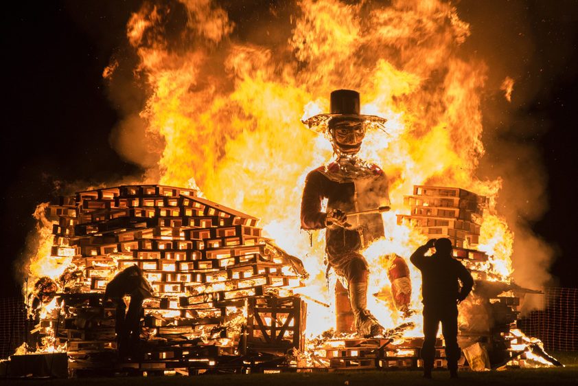 Man standing in front of a Guy Fawkes bonfire during the 5th of November at Lindifield bonfire night, West Sussex, England