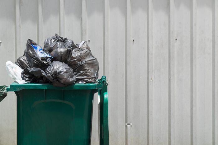 Green garbage bin with black garbage bags.