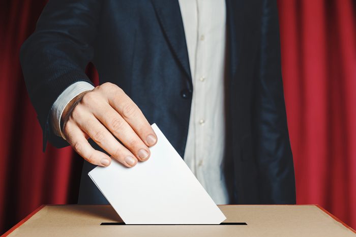 Man Voter Putting Ballot Into Voting box. Democracy Freedom Concept On Red Background