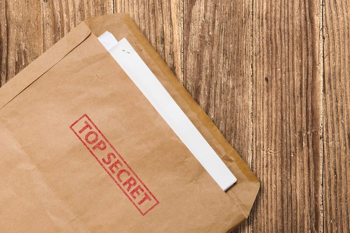 Open yellow envelope with top secret stamp and papers, on wooden table, clipping path.