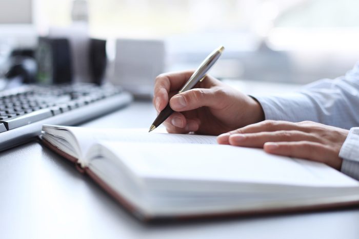 businessman writes in a notebook while sitting at a desk