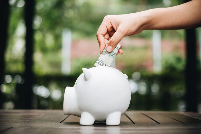 hand putting money bank note dollar into piggy for saving money 