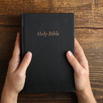 Women's hands holding the Bible. Top view.The concept of religion.