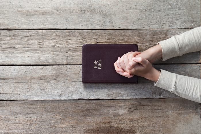 woman hands on bible. she is reading and praying over bible over wooden table