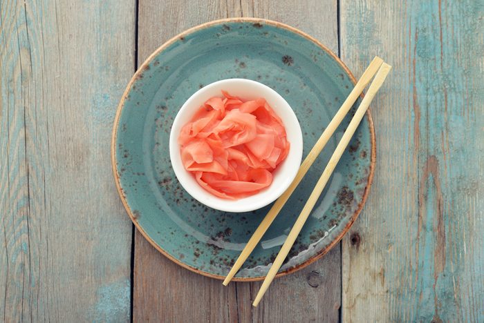Pickled ginger with wooden chopsticks on plate top view