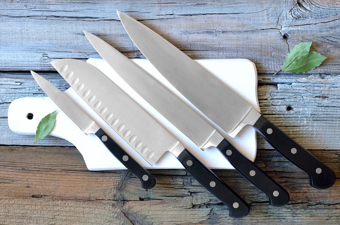 Set of kitchen knives on a board, top view