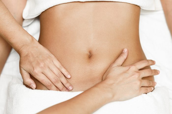 Top view of hands massaging female abdomen.Therapist applying pressure on belly. Woman receiving massage at spa salon