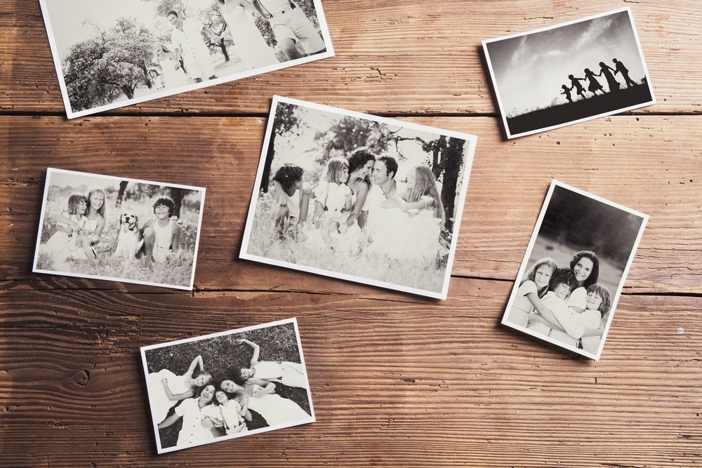 Black and white family photos laid on wooden floor background.