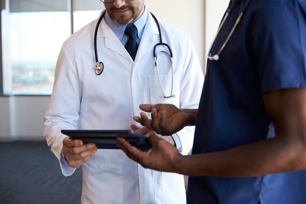 Close Up Of Hospital Staff Reviewing Notes On Digital Tablet