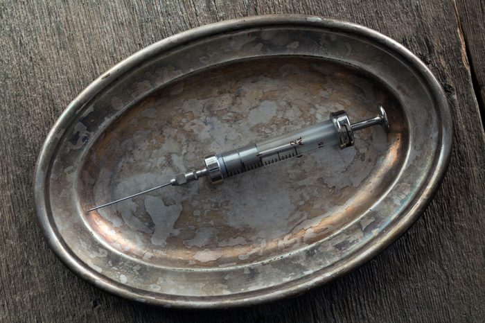 Glass syringe on an old silver tray