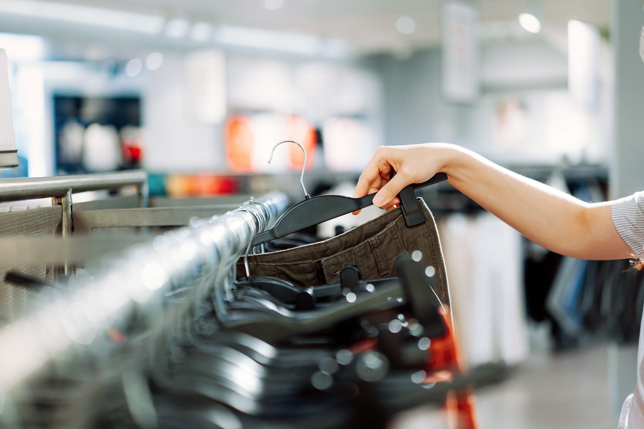 Close Up Of Woman's Hand Taking Out A Piece Of Garment From The Hanging Rail While Shopping At A Clothing Store In The City