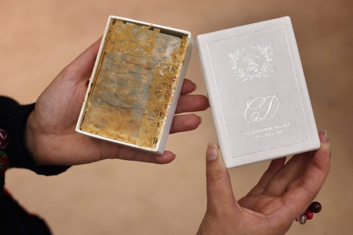 A woman holds a piece of wedding cake from the wedding of Prince Charles and Princess Diana in 1981 at the Olympia International Fine Art and Antiques Fair