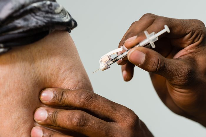 Close up of a syringe about to be injected into a patients arm.