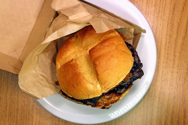 Thick-cut venison, topped with crispy onions, and juniper berry sauce. Venison steak venison sandwich, in wrapper and serving box. Overhead view, limited-edition Arby's venison sandwich