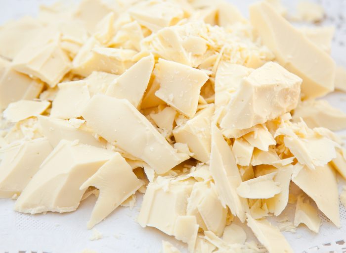 Pieces of cocoa butter, white chocolate on white paper.