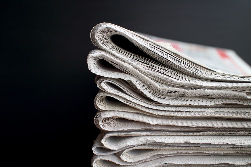 Stack of folded newspapers in front of a black background with copy space