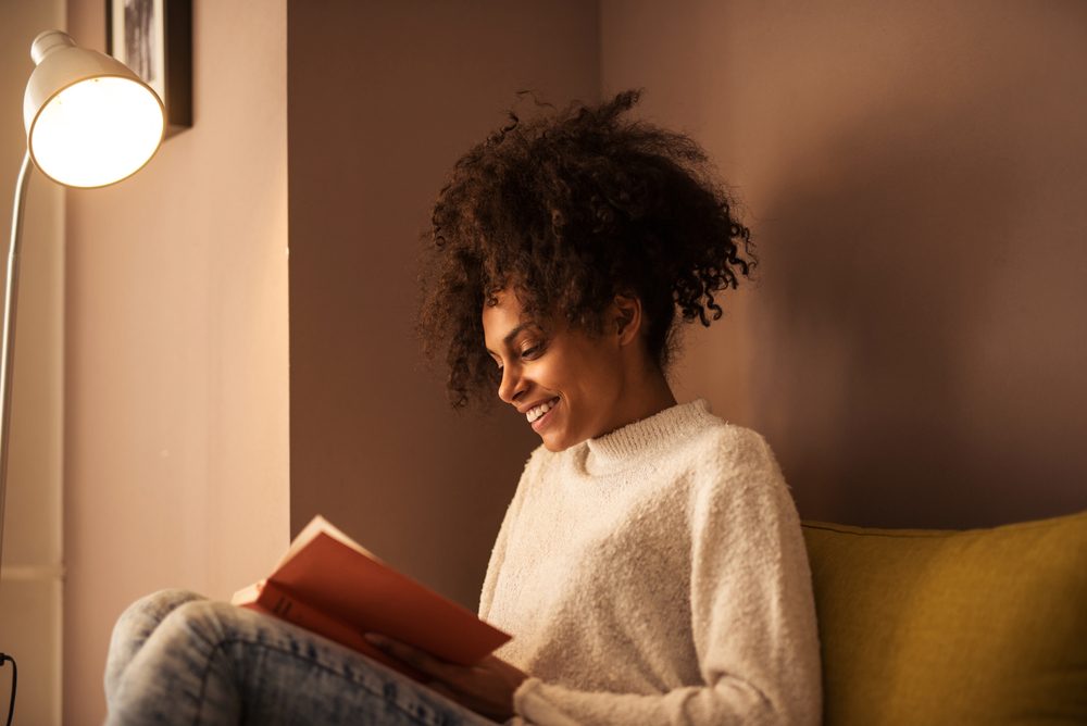 African american girl reading a book at home.