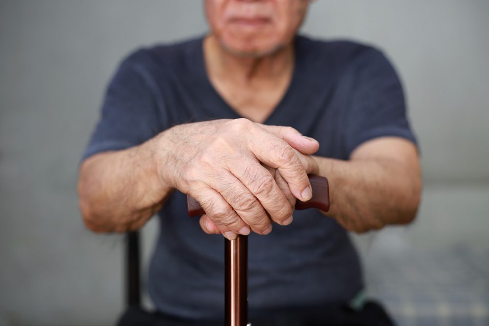 Close up of old man hand with walking stick.