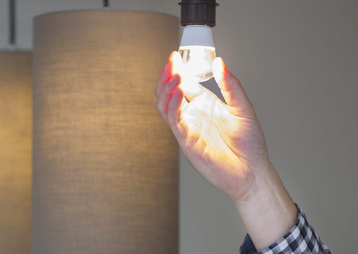 A man turning a lighted lightbulb in his own new house