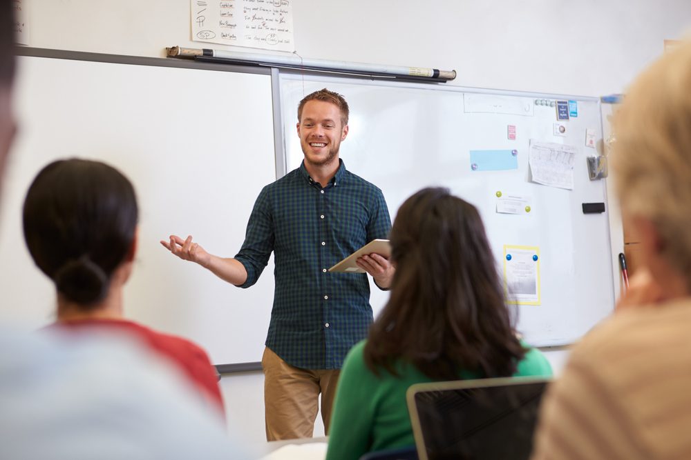 Male teacher listening to students at adult education class