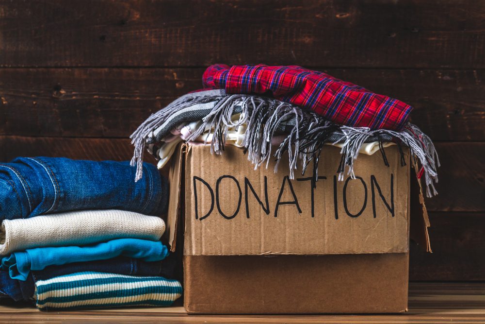 Donation concept. Donation box with donation clothes on a wooden background. Charity. Help for people in need