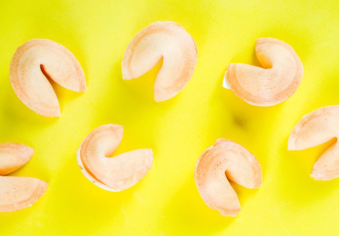 Chinese fortune cookie with prediction on bright yellow background top view copy space