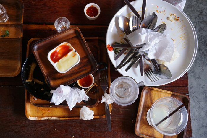 Messy table after party. Leftover food, spilled drinks, dirty dishes.