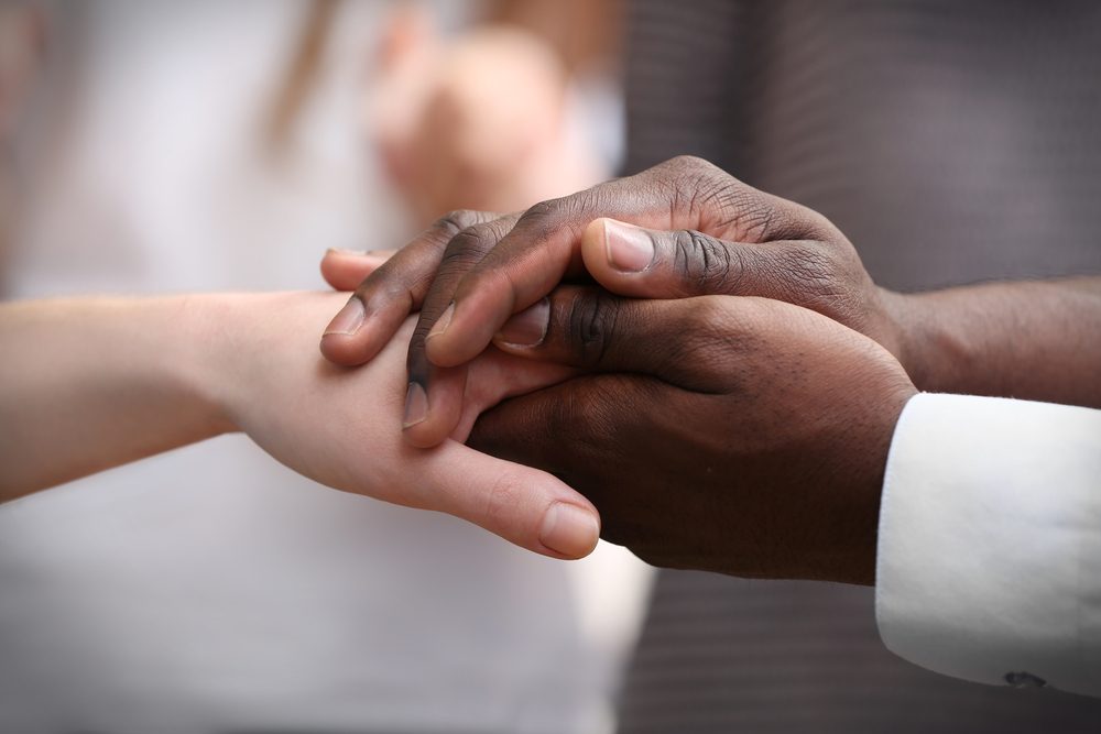 White caucasian and black afro american hands holding together, friendship concept